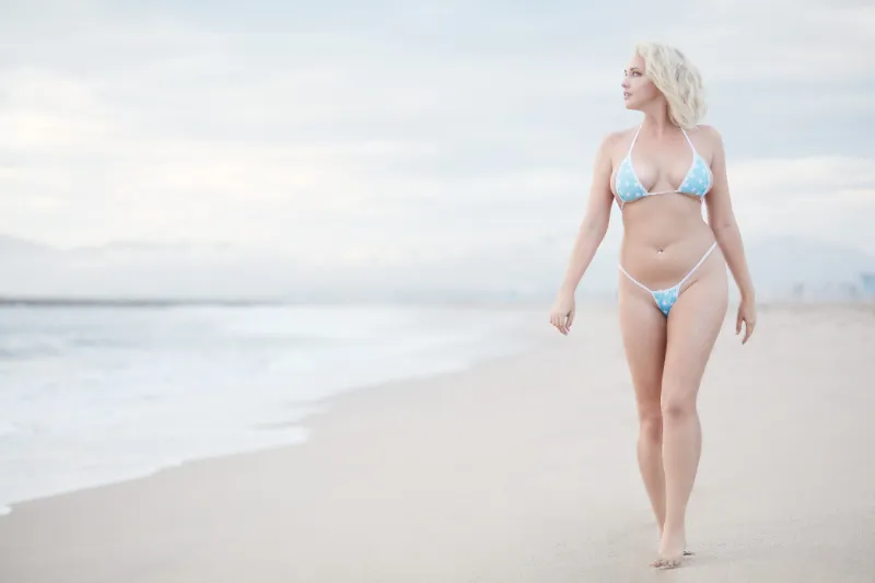woman in a bikini walking on the beach